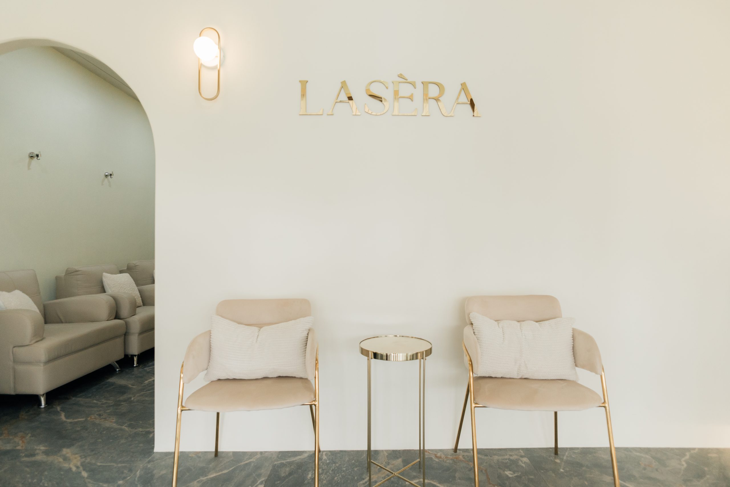 Lasera Skin Laser Center clinic interior — warm waiting lounge with gold Lasera signage